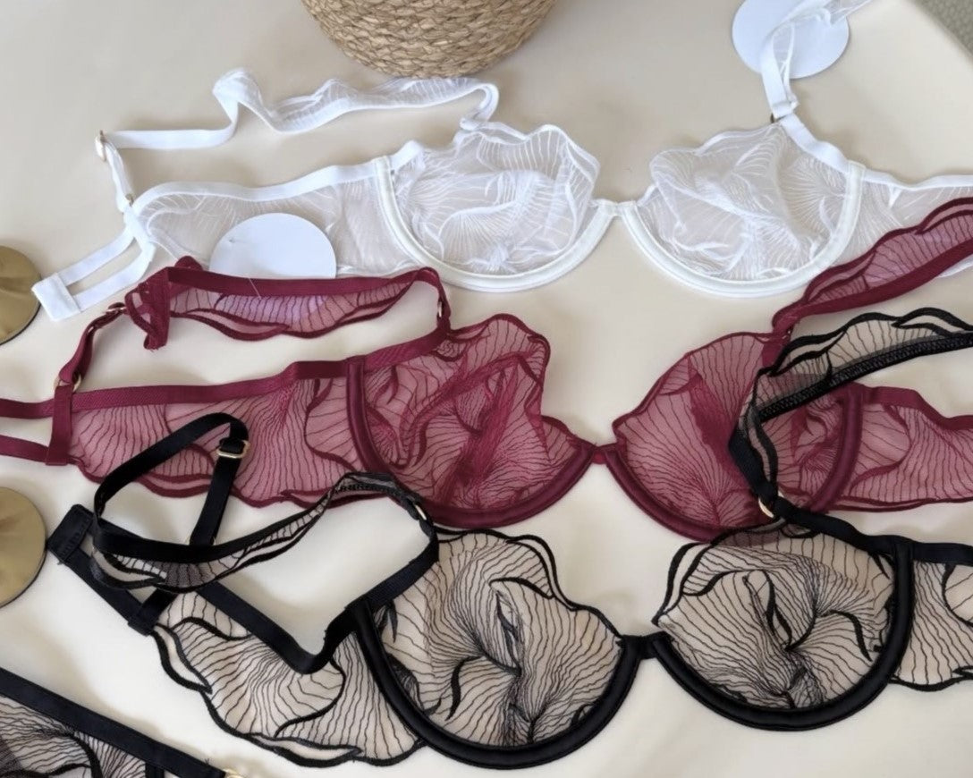 Odette Sheer Embroidered bras in black and burgundy arranged on a neutral surface.