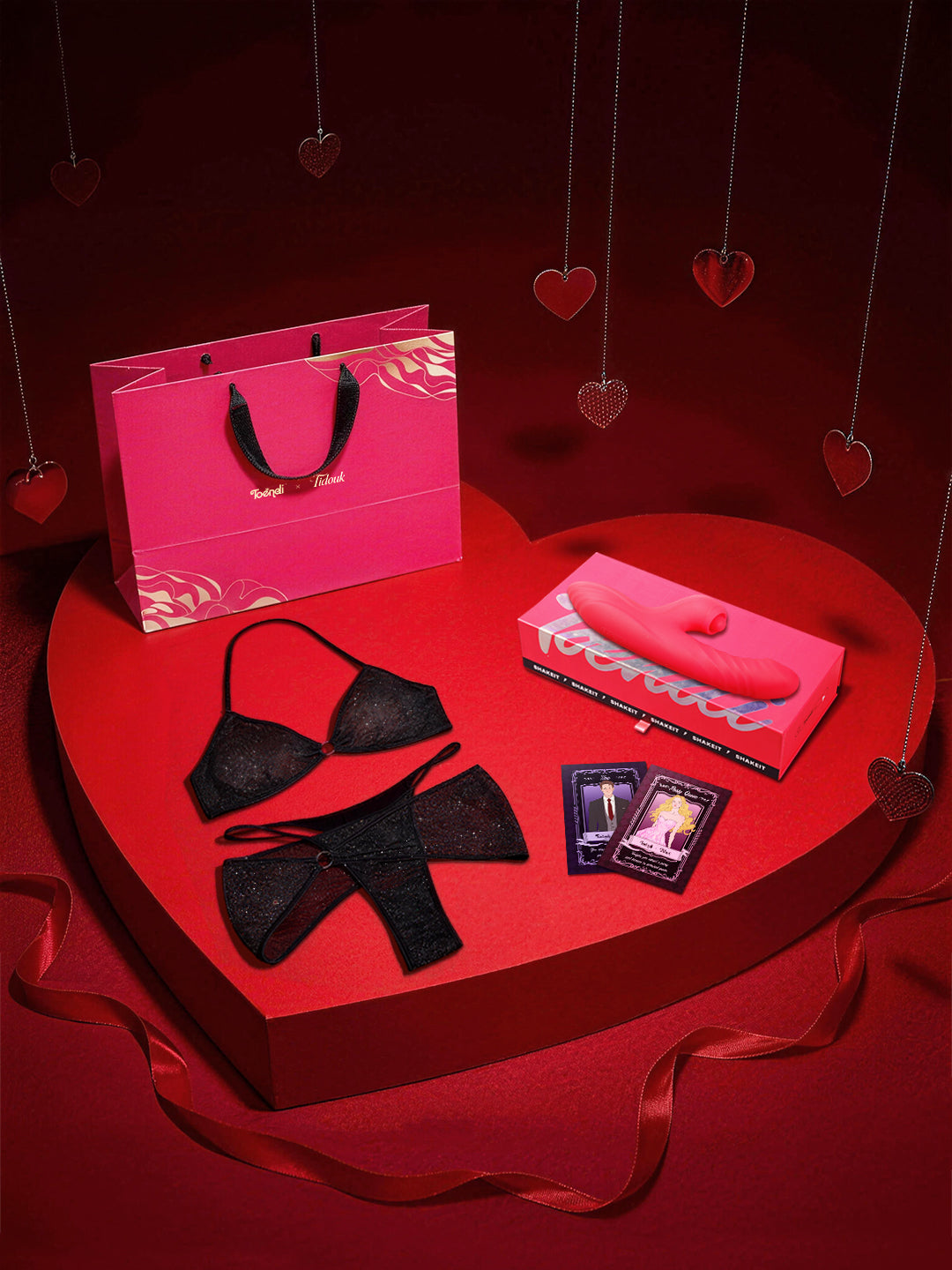 Red heart-shaped table with black lingerie, pink pouch, and pink shopping bag on a red background.