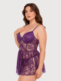 A woman modeling a purple lace babydoll lingerie chemise with underwire cups and thin spaghetti straps, set against a solid light gray background.