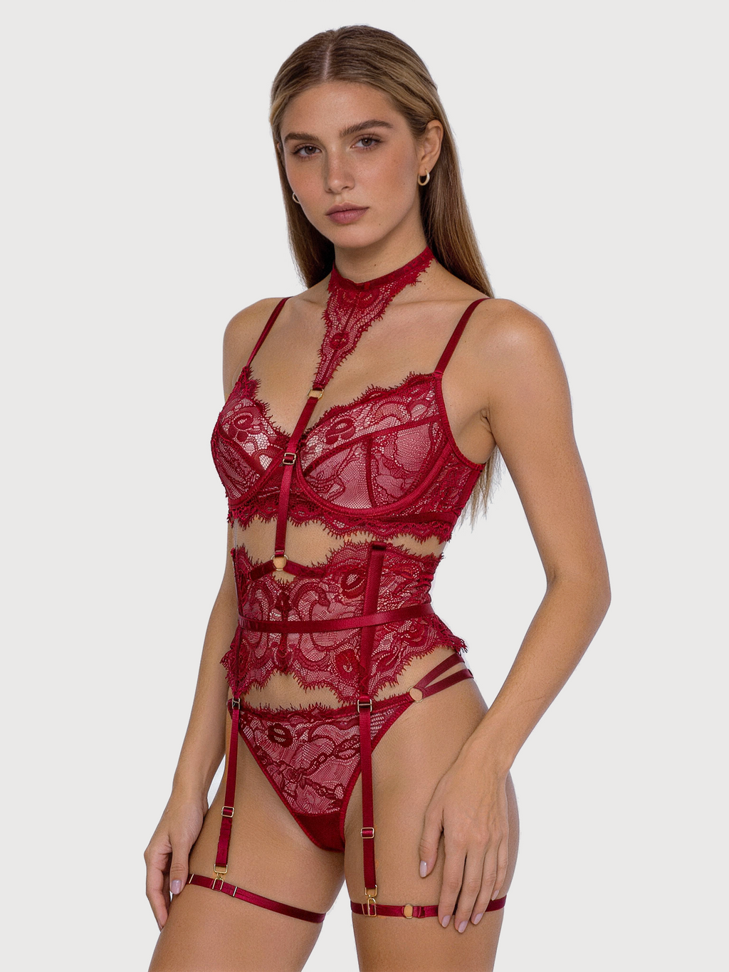 Woman wearing a red lace lingerie set on a plain background