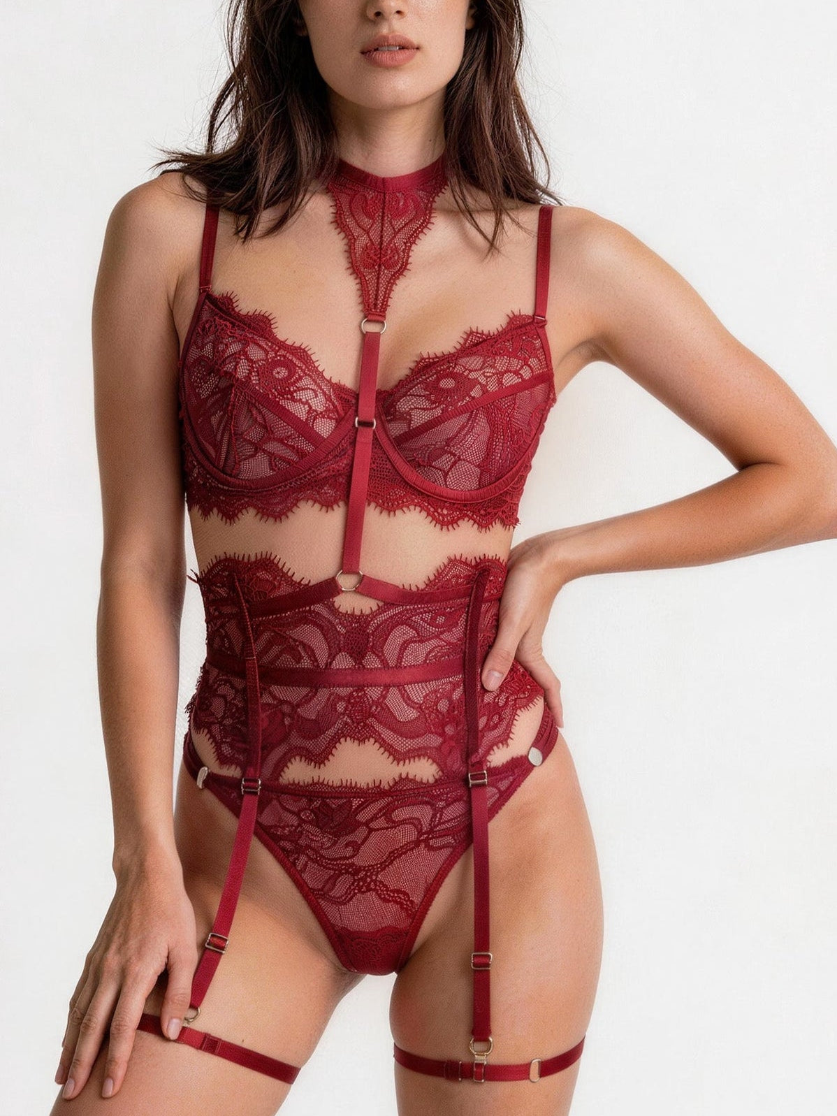 A woman modeling a red lace lingerie set with a high-neck collar, underwire bra, garter belt, and matching panties against a plain white background.